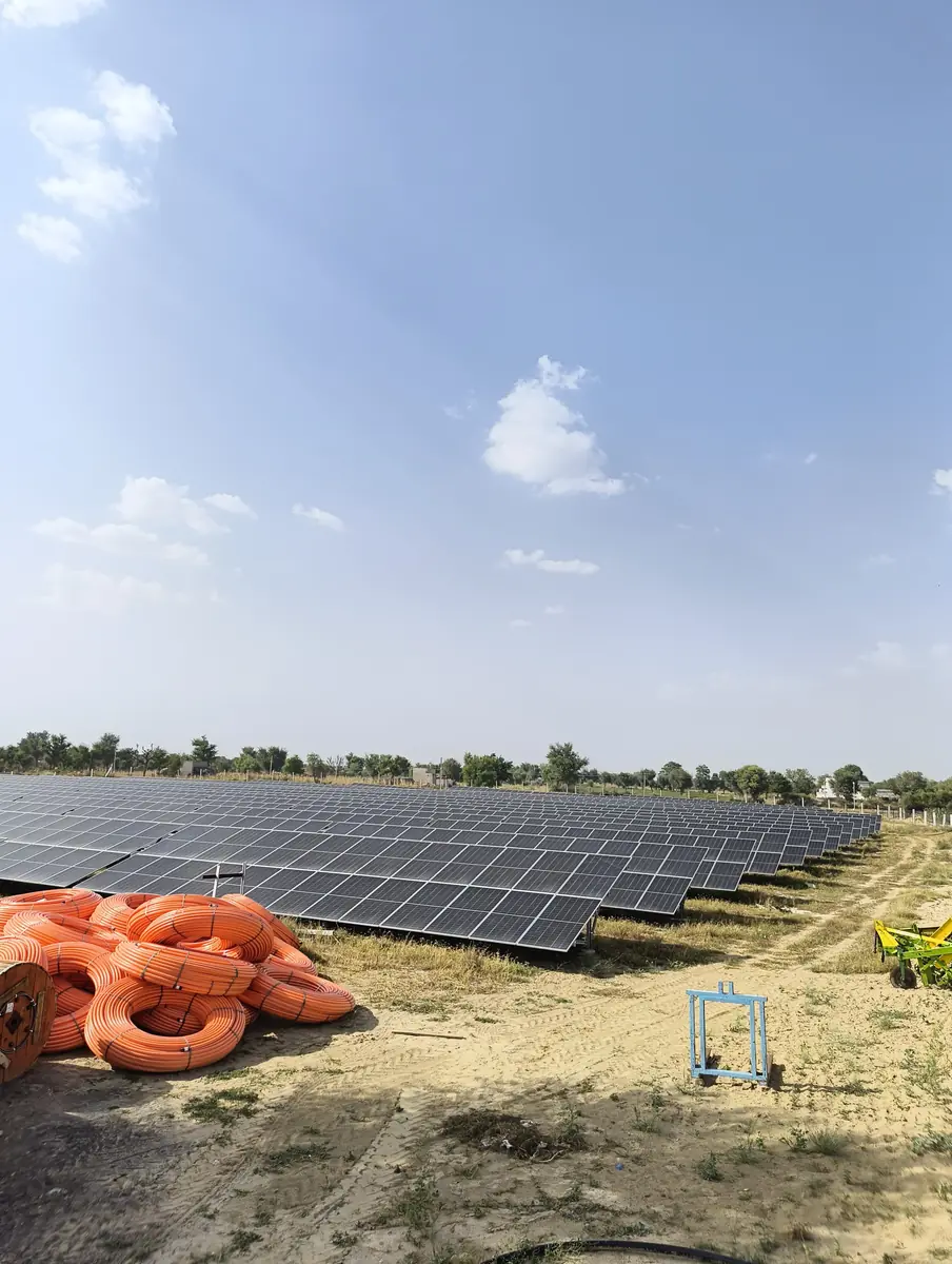 Solar module rows at the plant site with coils of orange cable in the foreground